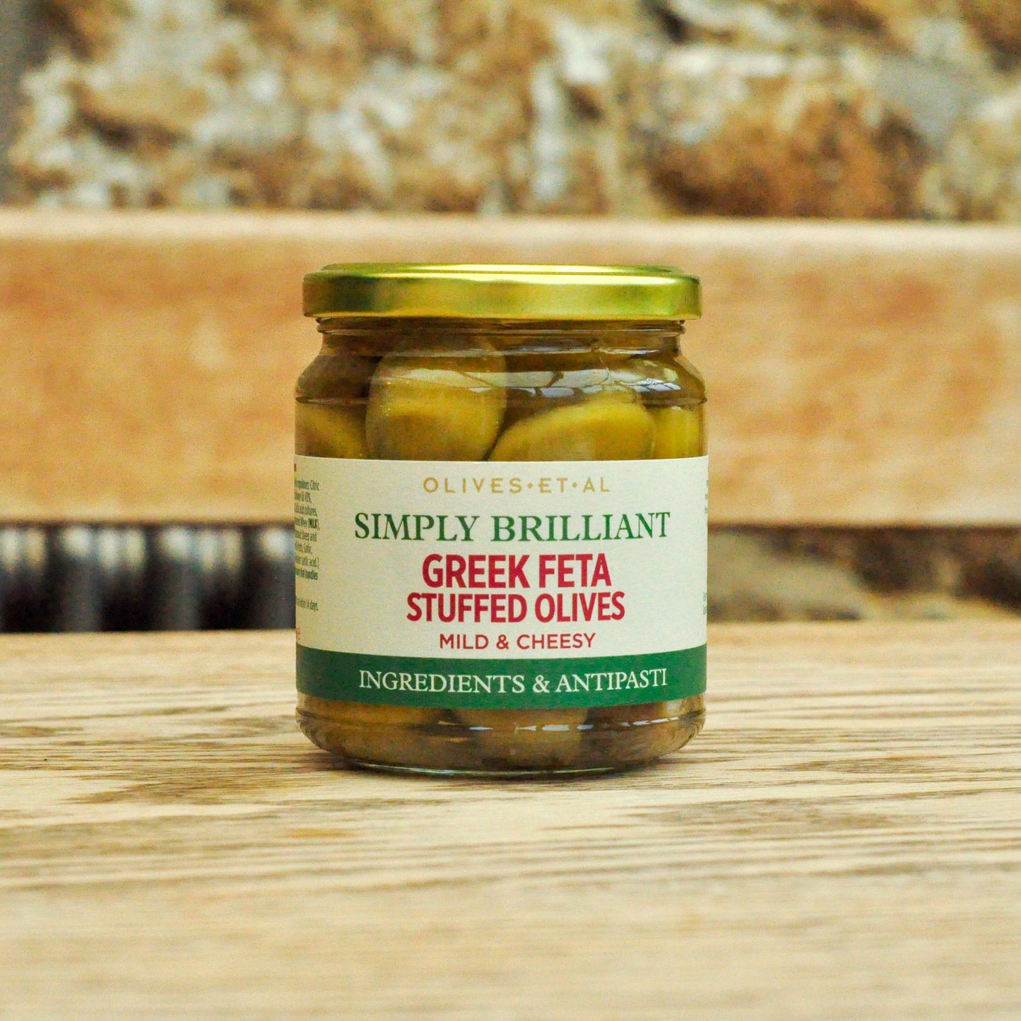 Jar of Greek Feta Stuffed Olives on a wooden surface with a blurred background