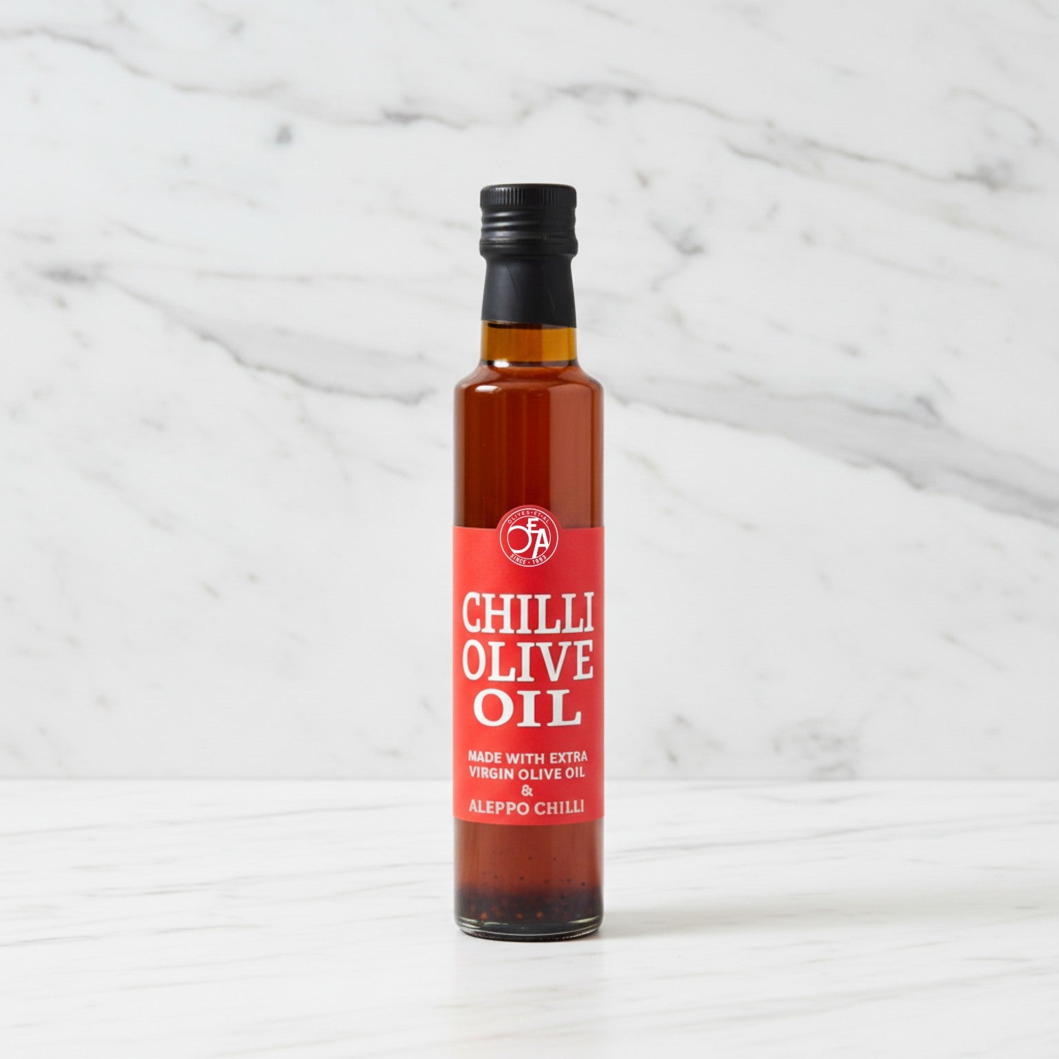 Bottle of Chilli Olive Oil with a red label on a white marble background