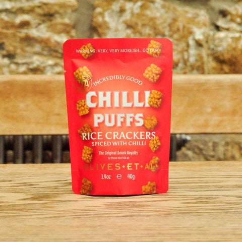Red package of Chilli Puffs Rice Crackers on a wooden surface with a blurred natural background