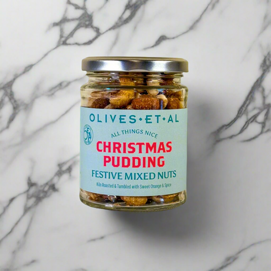 A jar of 'Olives & Al Christmas Pudding Festive Mixed Nuts' with a label indicating it is 'Pre-Order for Christmas'. The nuts are visible through the clear glass jar, showcasing their spiced and mixed appearance.