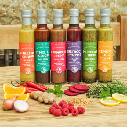 Assorted bottles of salad dressings with ingredients on a wooden surface
