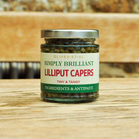 Jar of Lilliput Capers on a wooden surface with a blurred background
