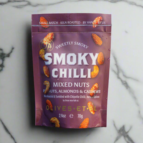 Purple package of smoky chilli mixed nuts on a wooden surface with a blurred green background