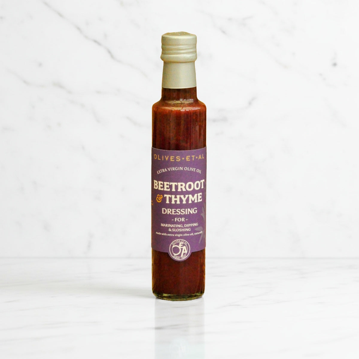 Bottle of beetroot and thyme dressing on a white background