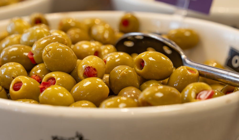 Bowl of olives with a spoon, branded 'Olives et al'.