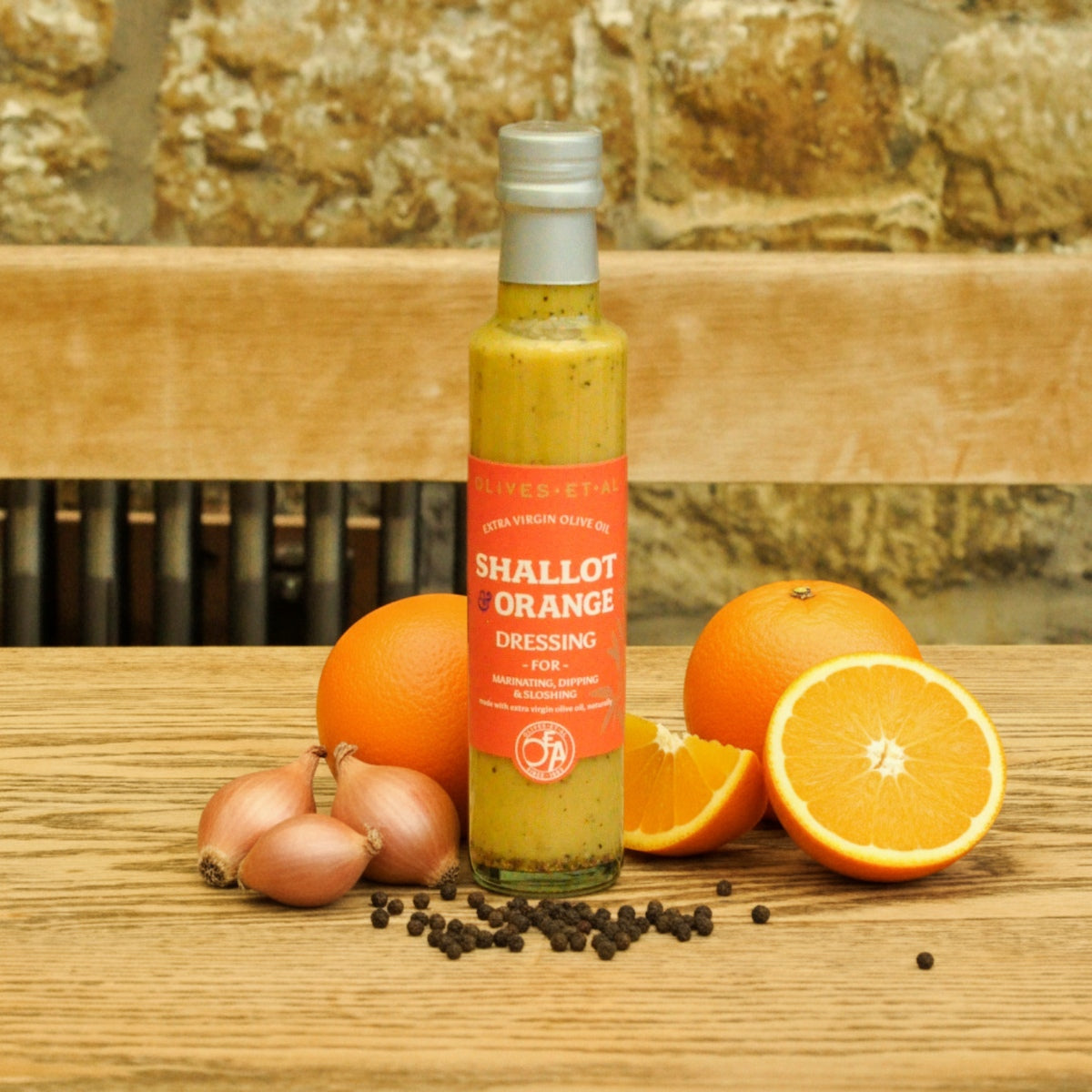 Bottle of 'Shallot Orange Dressing' with oranges and shallots on a wooden surface.