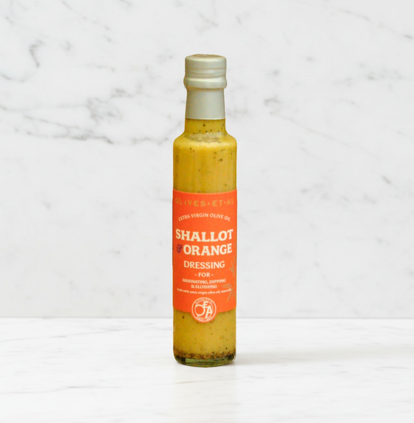 Bottle of 'Shallot & Orange' dressing on a marble background