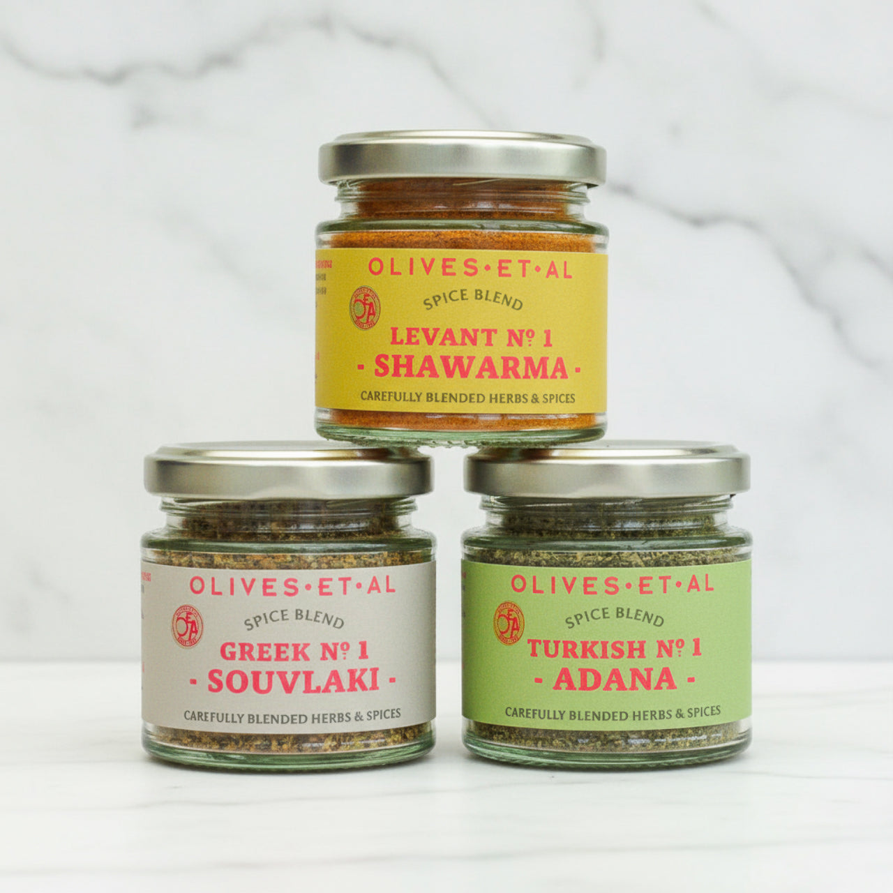 Olives Et Al Spice Blend trio on white marble background
